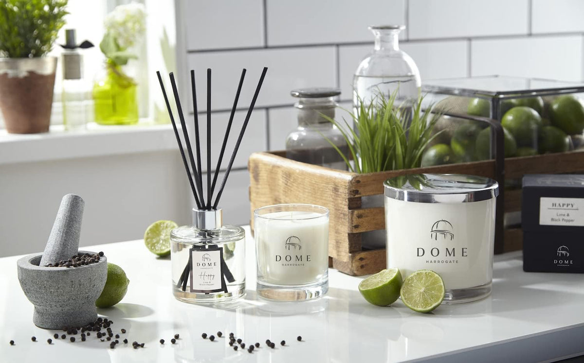A display of DOME home fragrance items including a reed diffuser with black reeds, a glass candle and a jar candle.